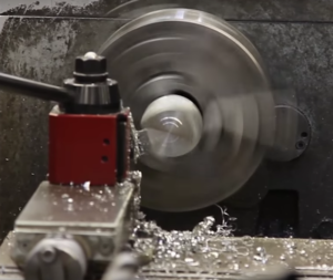 The sub-scale shoe being turned on the lathe. It looks like they are creating a conical surface that will parallel the conical tip of a standard pile. 